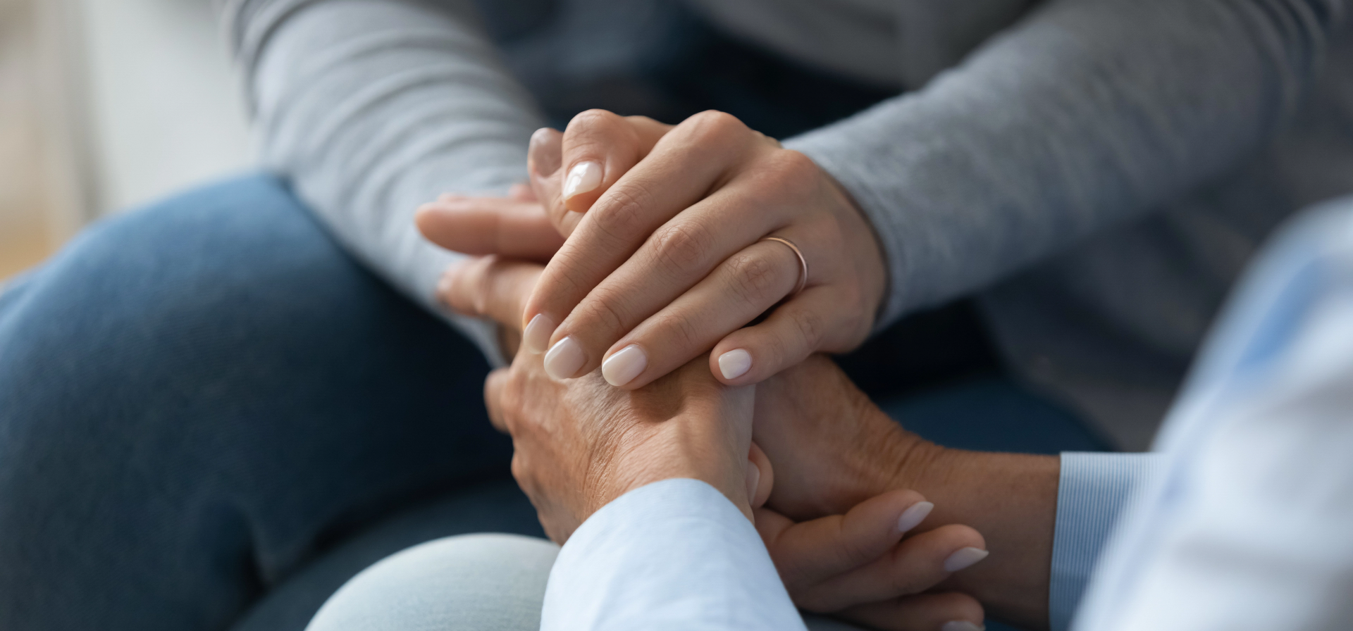 A close-up shot of two people holding hands in a comforting manner.